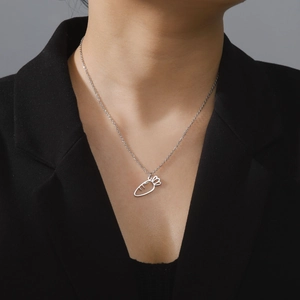 Detail of minimalist carrot pendant necklace worn by a model on a black blazer