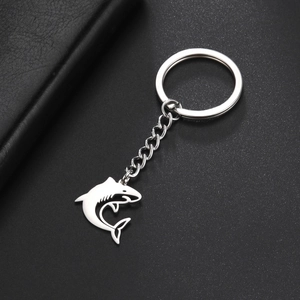 Detailed view of silver stainless steel shark pendant keychain on a dark textured background