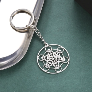 Detailed macro view of Metatron's Cube stainless steel keychain on a metallic tray