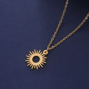 Detailed view of a golden sun pendant with a delicate cross chain on a blue background