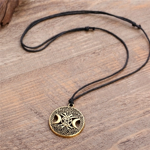 Macro detail of antique bronze Viking necklace with crescent moon and pentagram on wood