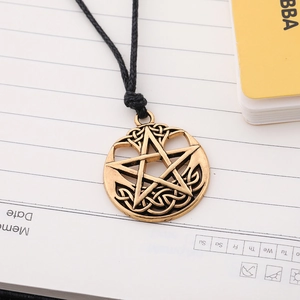 Detail view of retro bronze pentagram pendant with Celtic knot on a notebook