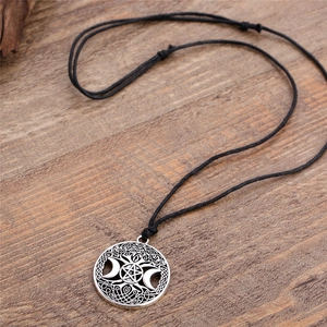 Detailed view of silver Viking moon and pentagram pendant necklace on wood
