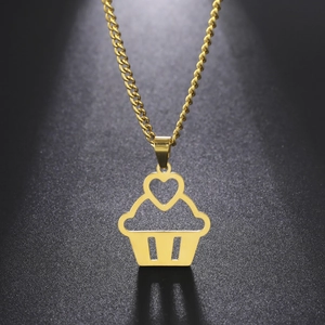 Détail du collier cupcake doré avec cœur évidé et chaîne cubaine sur surface noire