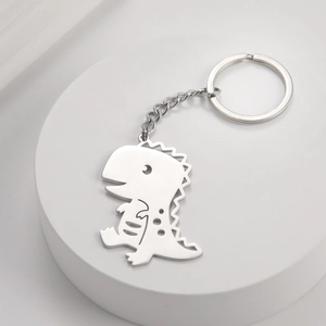 Polished stainless steel dinosaur keychain with laser-cut pendant on a white platform