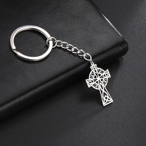Close-up of polished 304 stainless steel Celtic cross keychain on black leather background