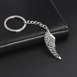 Detailed close-up of a silver hollow wing pendant on a punk style stainless steel keychain