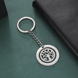 Polished stainless steel keychain featuring a hollow tree of life pendant on green background
