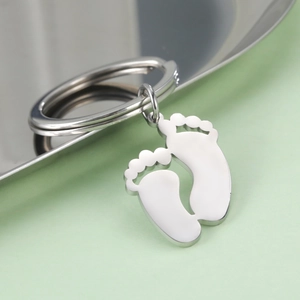Macro detail of polished stainless steel baby footprint charms on a keyring