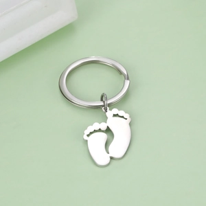 Macro detail of silver stainless steel keychain featuring a cute baby footprint pendant