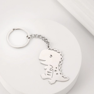 Detailed close-up of a hollow dinosaur pendant on a polished stainless steel keychain