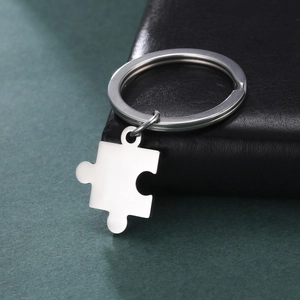 Porte-clés pièce de puzzle en acier inoxydable poli présenté sur du cuir noir élégant