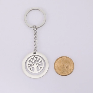 Size comparison of silver Tree of Life keychain next to a coin for scale reference