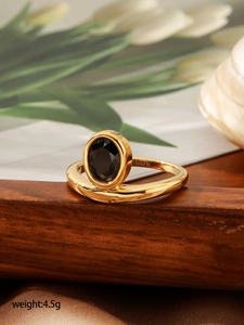 Dettaglio macro di un anello dorato con gemma nera su supporto in legno e incisione