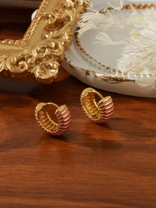 Close-up of vintage gold hoop earrings with pink enamel on a rustic walnut table