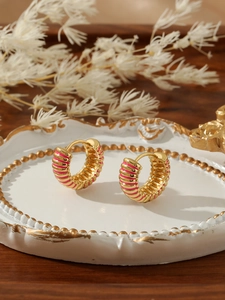 Detailed close-up of gold ear hoop with pink striped enamel on vintage relief tray