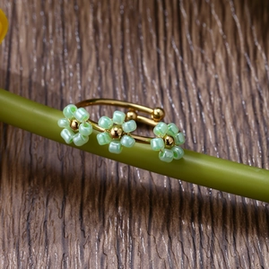 Detail view of adjustable gold ring with three green beaded flowers on plant stem