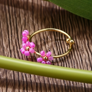 Macro shot of gold floral ring with purple resin beads on a textured wooden background