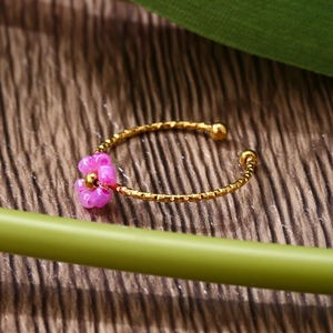 Detailed close-up of adjustable gold ring with purple bead flower and hammered texture