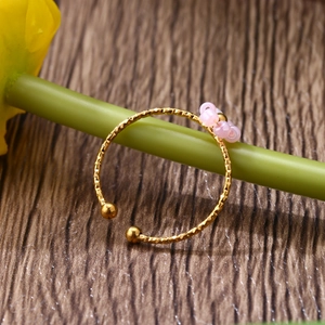 Detailed shot of adjustable ring with pink beads on a green stem with wood background