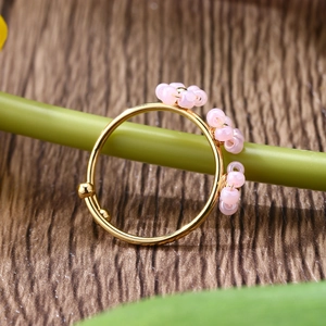 Macro detail of adjustable gold ring with pink beads hand-wrapped on floral design