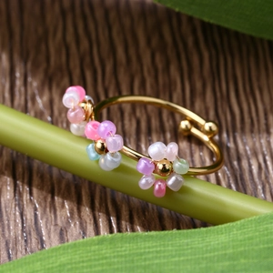 Macro shot of adjustable gold flower ring with colorful candy beads on a green stem