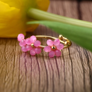 Macro shot of an adjustable gold ring featuring two pink faceted crystal flower charms