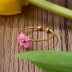Detailed close-up of pink beaded flower on a hammered gold adjustable ring band