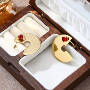 Dettaglio di orecchini a C placcati in oro con una pietra a cuore rossa in scatola porta gioie