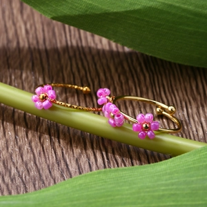 Detailed macro shot of adjustable gold ring with purple beaded flower on green plant stem