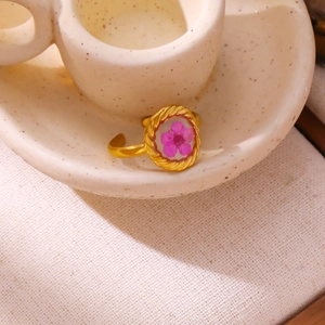 Detail of vintage gold-plated ring featuring a pink dried flower in oval resin