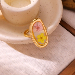 Detail of adjustable gold ring with pink and yellow dried flowers in resin oval