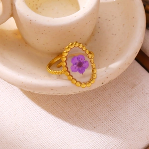 Detail of a vintage gold-toned ring with a real purple dried flower in clear resin