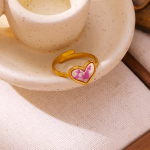 Detailed macro view of heart-shaped gold ring with purple dried flowers and adjustable band