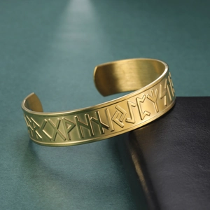 Macro detail of gold-plated stainless steel cuff featuring Nordic rune relief carving