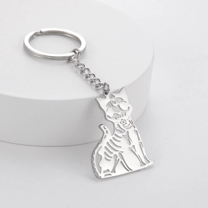 Skeleton cat cutout keychain made of polished stainless steel on a white pedestal