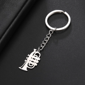 Detailed macro view of silver stainless steel trumpet musical instrument keychain on leather