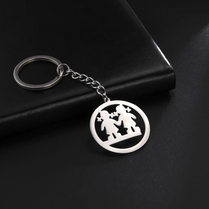 Polished stainless steel keychain with cutout girls pendant on black leather surface
