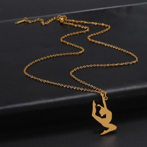 Nahaufnahme des goldenen Turnerin-Anhängers an einer Gliederkette auf schwarzem Leder
