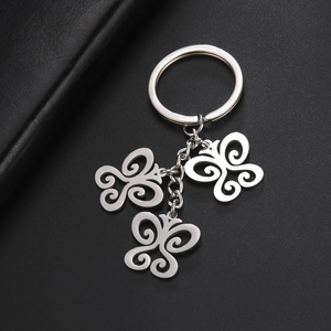 Polished silver butterfly keychain with hollow spiral patterns on a dark textured surface