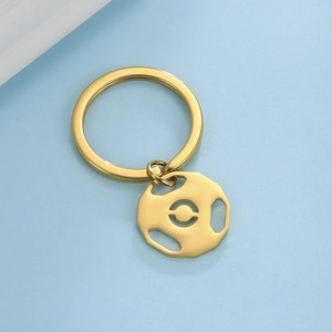 Macro detail of a golden stainless steel barbell pendant keychain on a blue background
