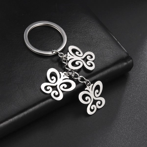 Detail of three hollow butterfly charms on a silver stainless steel keychain over leather