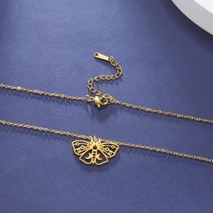Close-up of golden moth pendant with moon patterns and lobster clasp necklace detail