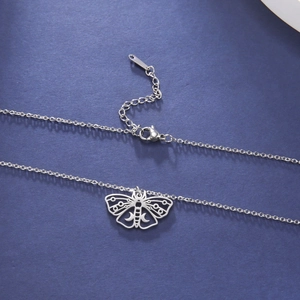 Macro detail of cut-out moth pendant and lobster clasp on O-chain stainless steel necklace