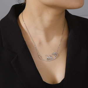 Close-up of giraffe and tree silhouette pendant necklace on model in black suit