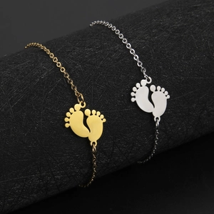 Détail de bracelets avec breloques pieds de bébé en or et argent sur un support noir
