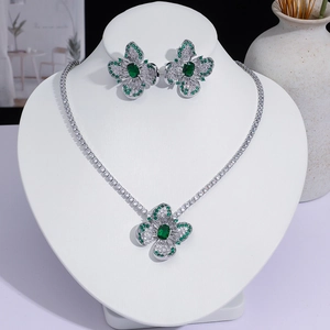 Vue détaillée du collier et des boucles d'oreilles trèfle émeraude de luxe avec pierres