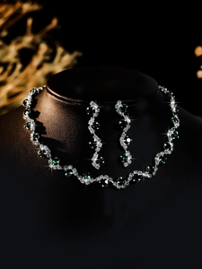 Close-up of bridal jewelry set with emerald green stones on black neck display