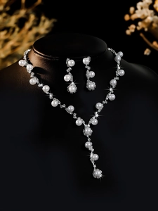 Detailed macro view of bridal jewelry set with pearls and zircons on black neck model