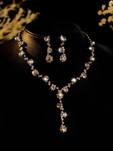 Detailed view of bridal jewelry set with sparkling pear-cut crystals on black background